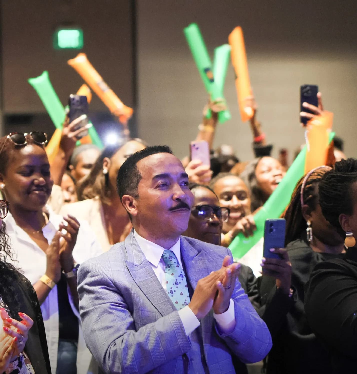 Dr David Molapo applauding among a cheering crowd holding noise-makers.