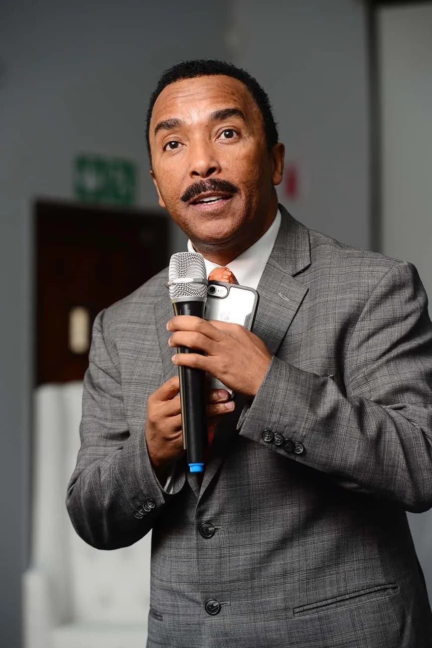 Dr David Molapo in a grey check suit, speaking.