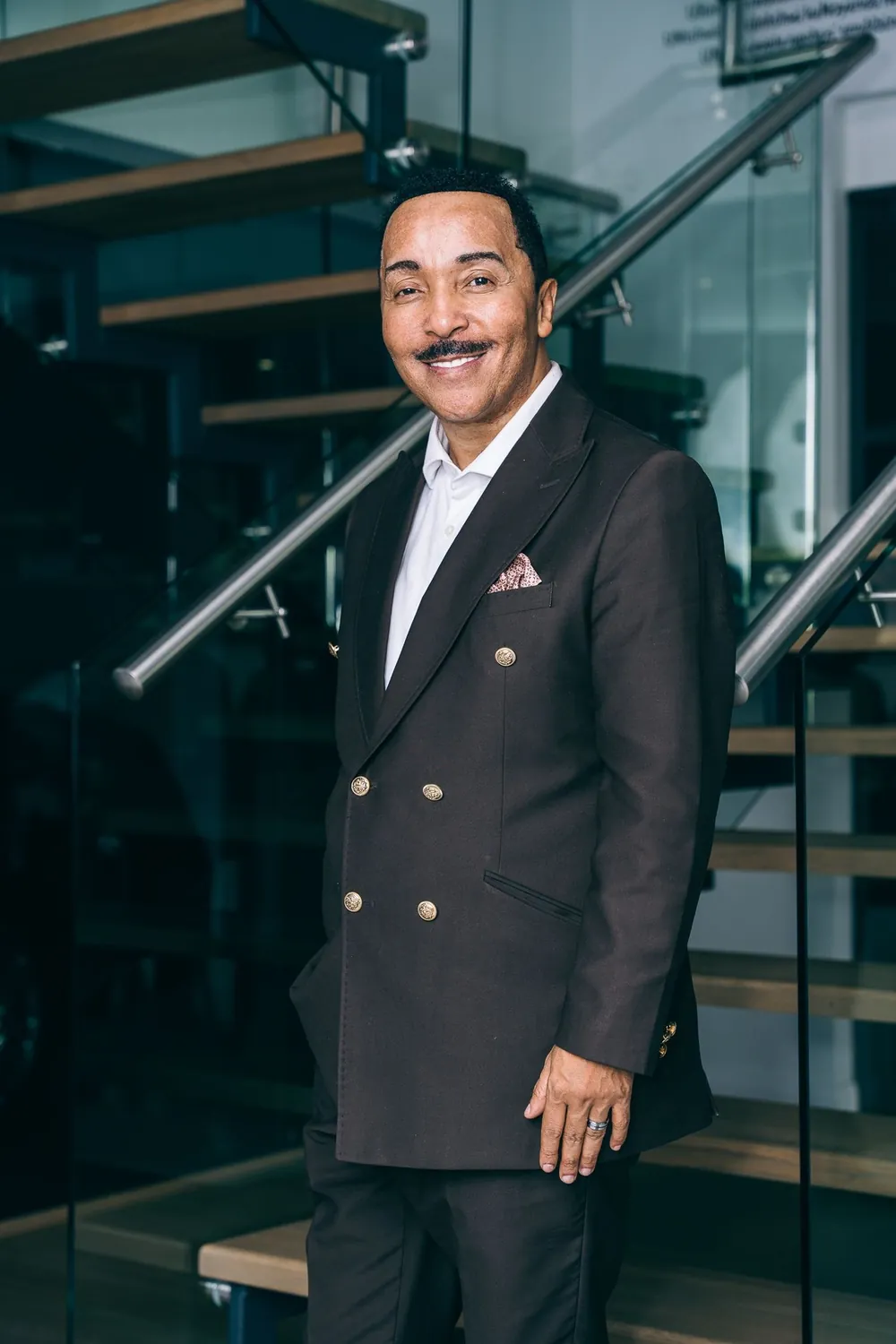 Dr David Molapo in a double-breasted suit beside a glass staircase.